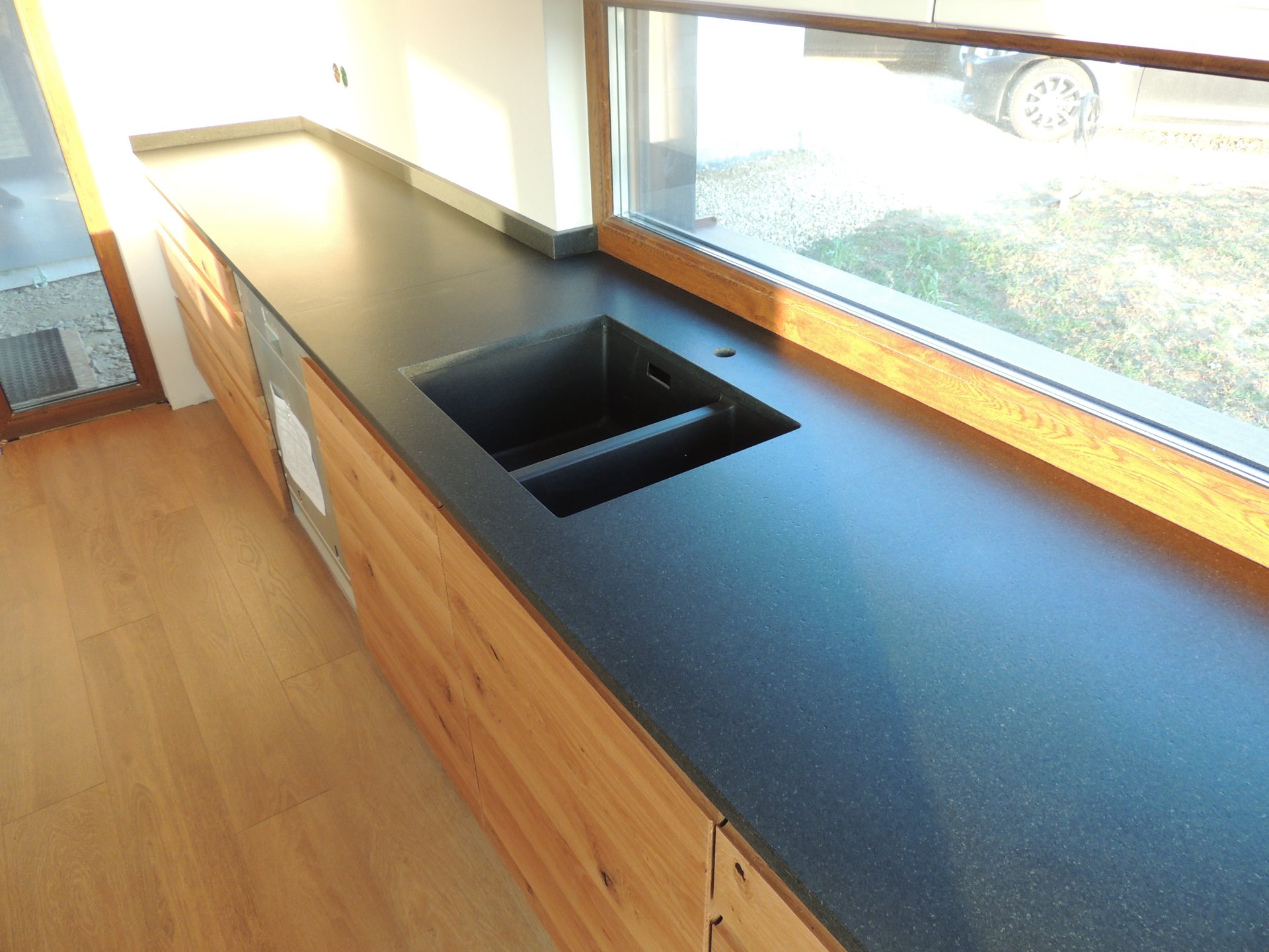 Nowoczesna jasna kuchnia z ciemnym granitowym blatem